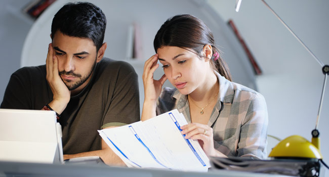 A sad and worried couple checking their financial papers Image